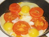 Разбиваем яйца в жареные помидоры